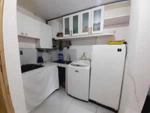uma cozinha branca com um frigorífico e um lavatório em ENCALADA em Otavalo
