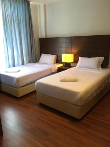 two beds in a hotel room with a window at Samsuria Private Beach Front in Kuantan