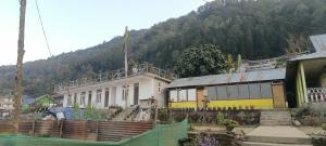 a yellow and white building in front of a mountain at Crystal Cottage in Pedong