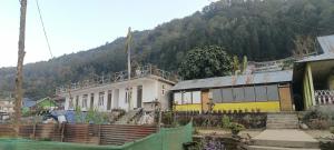 ein gelbes und weißes Gebäude vor einem Berg in der Unterkunft Crystal Cottage in Pedong