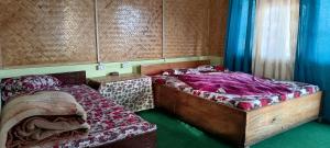 two beds in a bedroom with blue curtains at Crystal Cottage in Pedong
