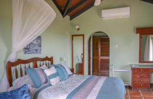 Schlafzimmer mit einem Bett mit blauen und violetten Kissen in der Unterkunft Calypso Court - Private 1 bedroom villa with pool villa in Cap Estate
