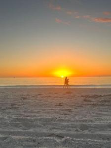 zwei Menschen, die bei Sonnenuntergang am Strand spazieren gehen in der Unterkunft Classic Floridian Oasis w/Pool in North Port