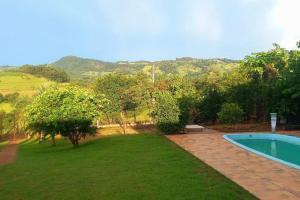 une arrière-cour avec une piscine et une pelouse avec des arbres dans l'établissement Recanto São Gabriel Socorro/SP chácara com linda Vista, à Socorro