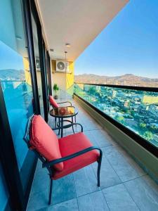 a room with a red chair and a table on a balcony at Luxury 1BR Apartment in Astria 706 in Tegucigalpa
