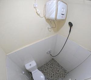 a bathroom with a toilet and a phone on the wall at Omah Sidoarum Homestay Jogja in Godean