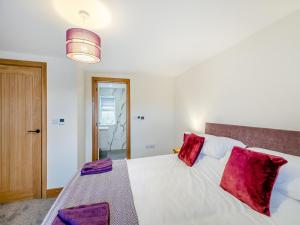 a bedroom with a large white bed with red pillows at Home Farm Cottage in Sawley