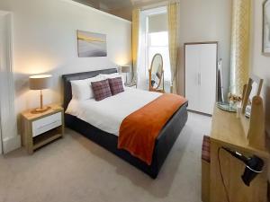 a bedroom with a large bed and a mirror at Flat 3, Barron House in Nairn