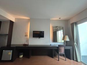 Zimmer mit einem Schreibtisch, einem TV und einem Spiegel in der Unterkunft โรงแรม ดิ โอวาเล่ย์ [The O Valley Boutique Hotel] 