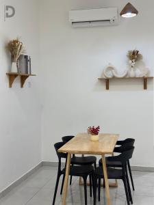 a dining room table with black chairs and a white wall at DE WHITE HOMESTAY . PORT DICKSON in Port Dickson