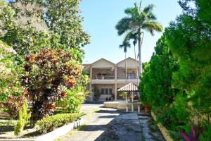 una casa grande con una palmera delante de ella en Villas Del Ángel - El Naranjal, en La Ceiba