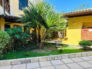 a palm tree in front of a yellow house at Iguaba Grande, 3 minutos do mar in Iguaba Grande