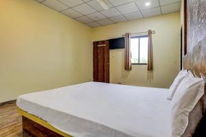 1 dormitorio con 1 cama blanca grande y ventana en Super OYO Neelkanth Hotel And Restaurant en Vadodara