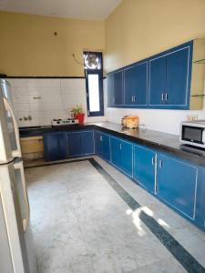 una grande cucina con armadi blu e una finestra di Shantiniketan - Comfortable Stay in Ayodhya a Ayodhya