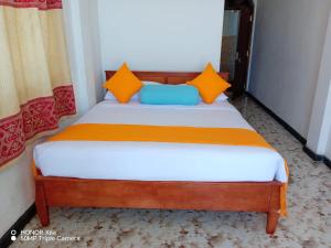 1 dormitorio con 1 cama con almohadas de color naranja y azul en Grand Glorious, en Haputale