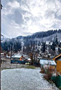 a snow covered hillside with houses and trees at Forest inn pahalgam in Anantnāg