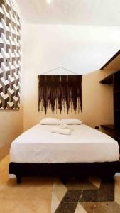 a bedroom with a bed with white sheets and a wall at Ko'ox 52 in Mérida