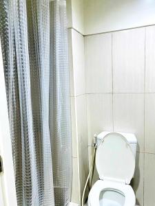 a bathroom with a toilet and a shower curtain at D'Hideout in shell residences moa pasay in Manila