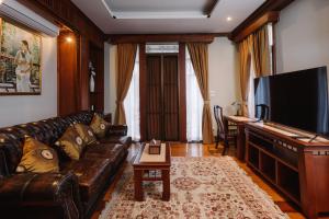 sala de estar con sofá de cuero y TV de pantalla plana en Lunar Mansion Hotel, en Chiang Mai