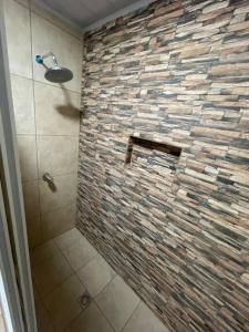 a bathroom with a shower with a stone wall at Casa del Ángel #10 in La Ceiba
