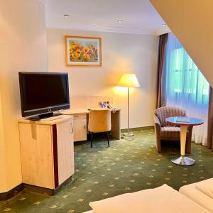 a hotel room with a flat screen tv and a desk at Landhotel Heimathenhof in Heimbuchenthal