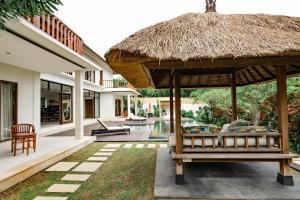 a pavilion with a bench and a straw umbrella at Casa Margarita Bali in Canggu