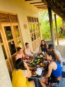un grupo de personas sentadas alrededor de una mesa con comida en Ayubowan Hiriketiya, en Dikwella