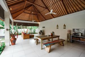 una sala de estar de planta abierta con mesa de madera y banco. en Casa Margarita Bali, en Canggu