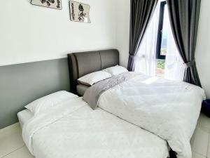 two beds in a bedroom next to a window at Decozy 8.0 IpohTownCondo (10pax) in Ipoh