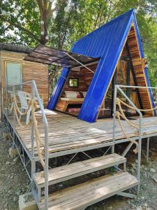 a cabin with a blue roof and a deck at Arzel Resort in Mangatarem