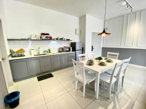 a kitchen with a white table and white chairs at Decozy 8.0 IpohTownCondo (10pax) in Ipoh