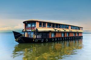 a boat in the water with a building on it at Harmony Houseboats in Alleppey