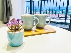 three white vases sitting on a table with purple flowers at Decozy 8.0 IpohTownCondo (10pax) in Ipoh