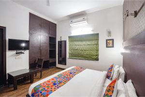 Dormitorio con cama, escritorio y TV en FabHotel City Chalet Saket, en Nueva Delhi