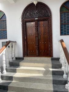 a set of stairs leading to a wooden door at Nashu House Stone Town in Ngambo
