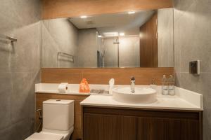 a bathroom with a sink and a toilet and a mirror at The Proud Karon Beach Phuket Trademark Collection By Wyndham in Karon Beach