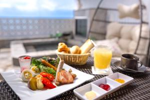 una mesa con un plato de comida y un vaso de zumo de naranja en Hotel Noir Blanc en Shizuoka