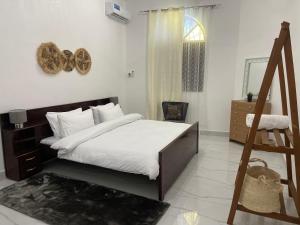 1 dormitorio con 1 cama con sábanas blancas y ventana en Nashu House Stone Town en Ngambo