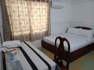 um quarto com 2 camas, uma mesa e uma cadeira em CENTRO GUEST HOUSE em Siem Reap