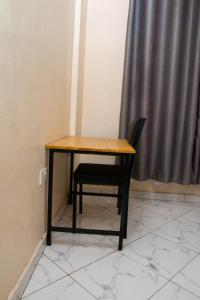 a wooden table and a chair sitting in a room at Beach Box Dimash Apartments in Mombasa