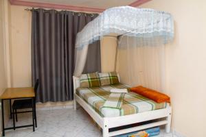 een klein bed met een baldakijn in een kamer bij Beach Box Dimash Apartments in Mombasa