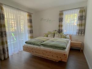 a bedroom with a bed in a room with windows at Wohnen am Almufer - Ferienwohnung Straßmair in Grünau im Almtal