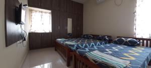 um quarto com duas camas e uma televisão na parede em Shantham Service Apartments, Indumanagar, Coimbatore em Coimbatore