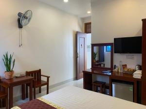 a room with a bed and a desk and a fan at ĐÔNG ĐÔ HOTEL Đăk Lăk in Buôn Tâng Mai