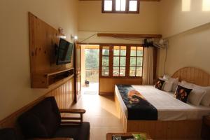 a bedroom with a bed and a tv and a couch at Purnima Guest House, Old Kasol in Kasol