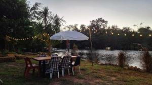 a table with chairs and an umbrella next to a lake at บ้านกลางโดม Baan Klang Dome 