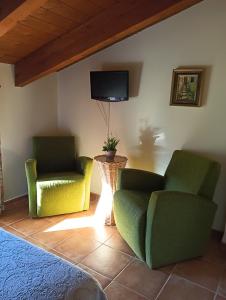 a living room with two chairs and a tv at Hostal Sol de la Vega in Albarracín