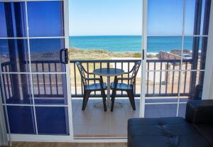 una mesa y sillas en un balcón con vistas al océano en Seaspray Beach Holiday Park en Dongara