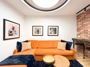 an orange couch in a living room with a fireplace at 2bdr Luxury Fully Equipped Prime Location in Sofia