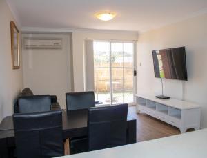a living room with a table and chairs and a television at Seaspray Beach Holiday Park in Dongara